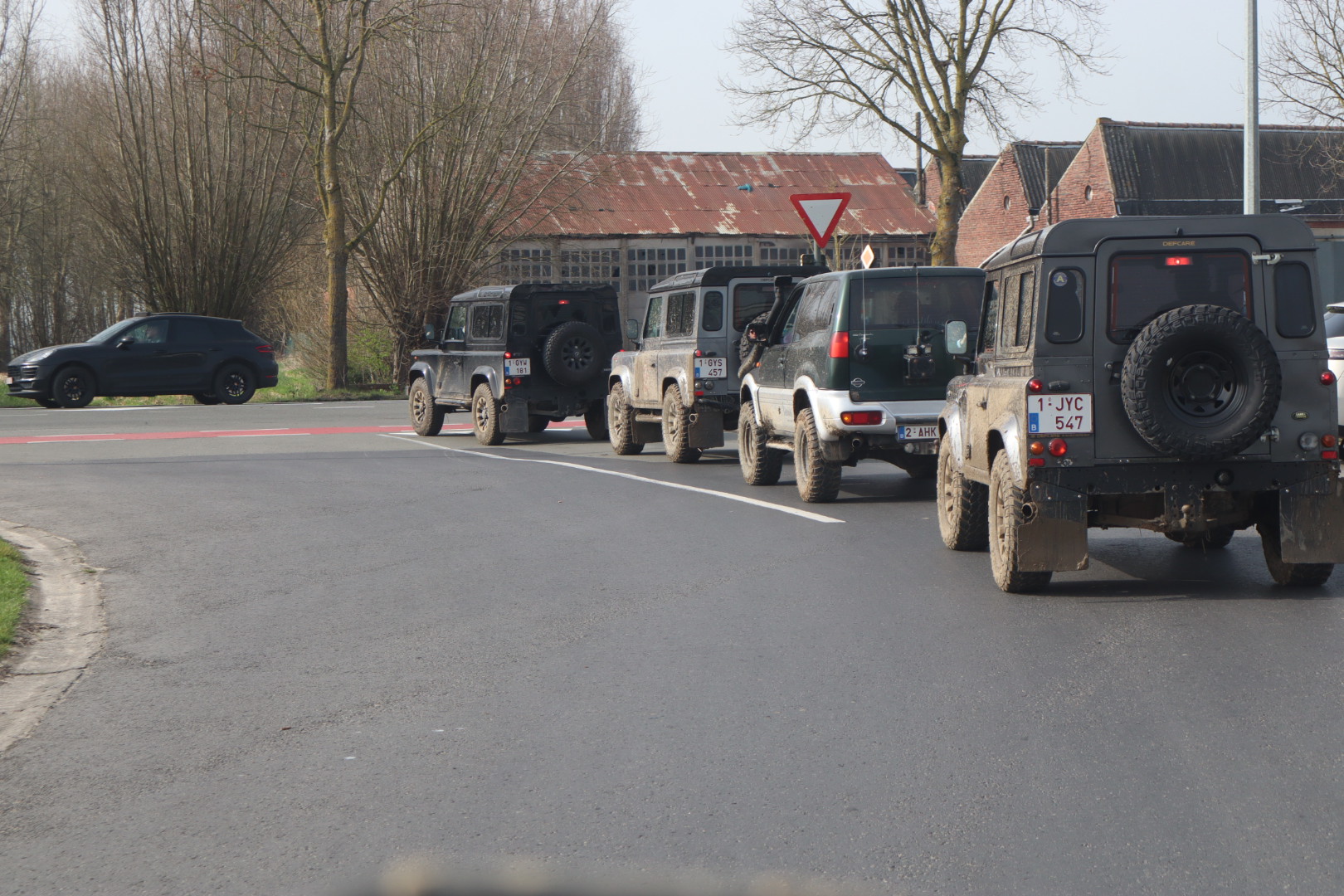 Modderige terreinwagens rijden samen door het Vlaamse landschap